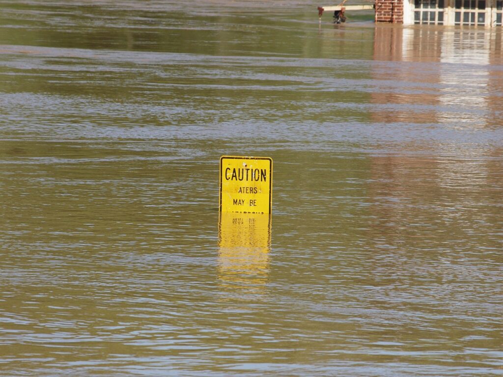 House and road partially submerged in floodwater, illustrating the importance of flood insurance for protecting homes from flood damage.